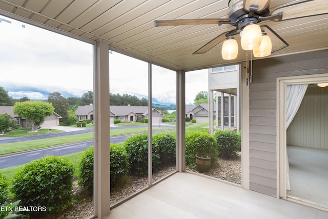 unfurnished sunroom with a ceiling fan, a residential view, and wooden ceiling