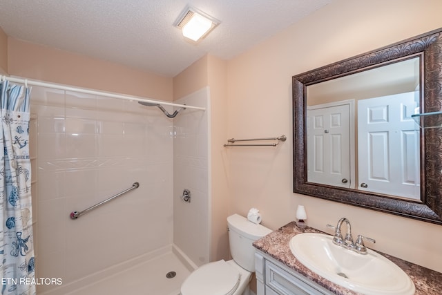 bathroom with toilet, a tile shower, a textured ceiling, and vanity