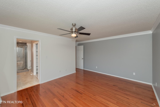 empty room featuring a ceiling fan, a textured ceiling, ornamental molding, and wood finished floors