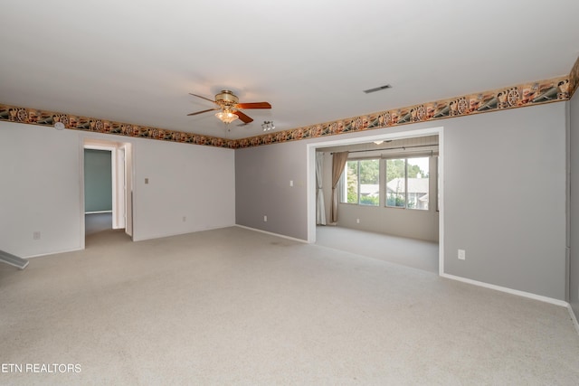 empty room with ceiling fan, baseboards, visible vents, and light colored carpet