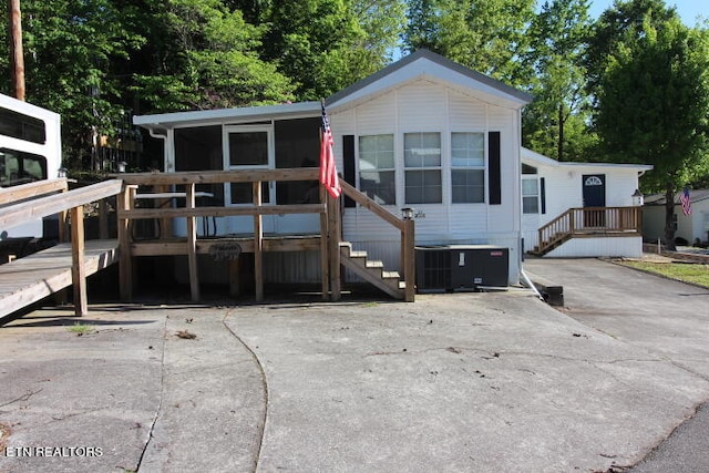 view of front of home with central air condition unit, a sunroom, and a deck