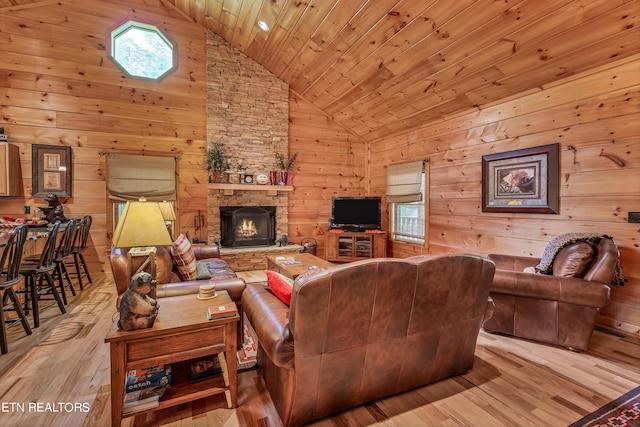 living room with light hardwood / wood-style floors, wooden walls, and a fireplace