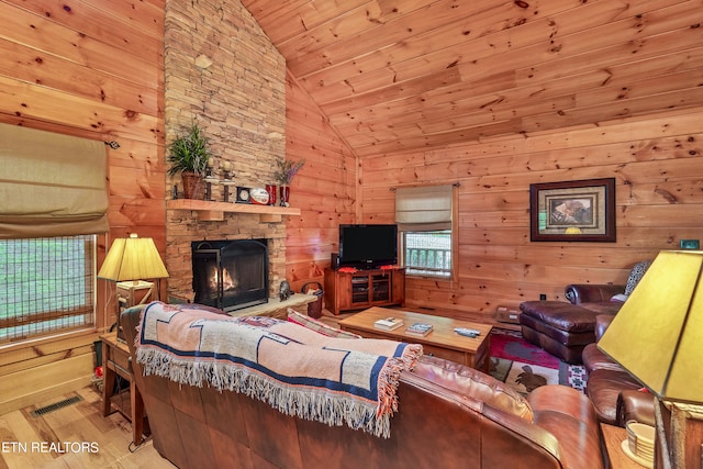 living room featuring a stone fireplace, light wood-type flooring, wood ceiling, lofted ceiling, and wooden walls