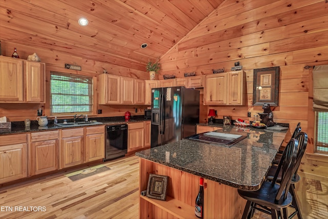 kitchen with wooden walls, a kitchen breakfast bar, black appliances, vaulted ceiling, and light hardwood / wood-style floors