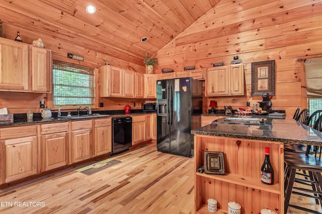 kitchen with wood walls, vaulted ceiling, light wood-type flooring, and black appliances