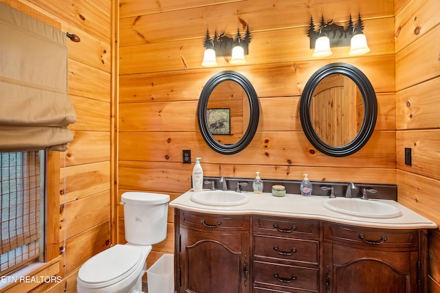 bathroom with toilet, dual vanity, and wooden walls