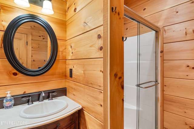 bathroom with an enclosed shower, vanity, and wooden walls