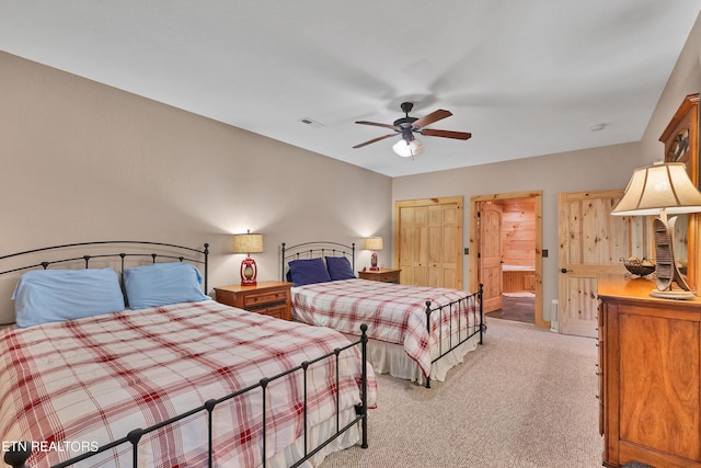 bedroom featuring light colored carpet, ceiling fan, and ensuite bathroom