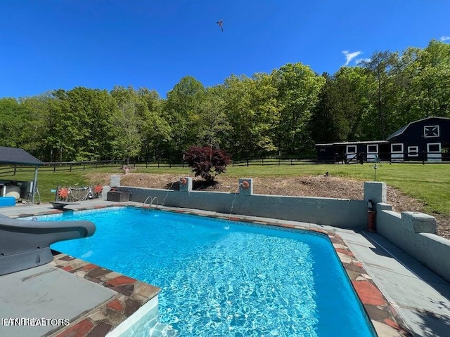 view of pool with a patio area, a water slide, and a lawn