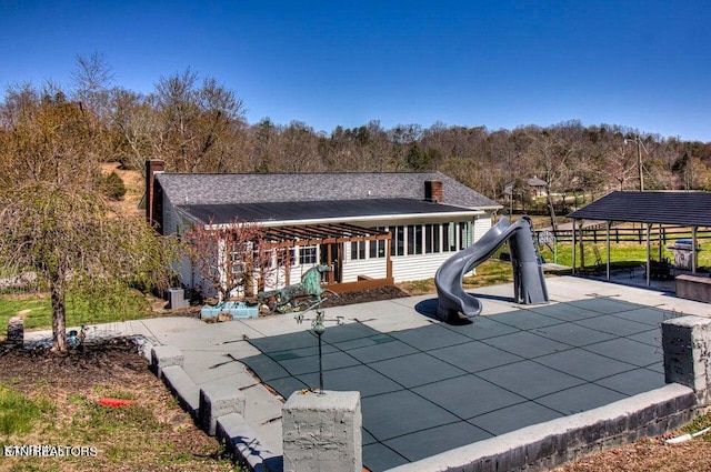 back of property with a playground and a covered pool