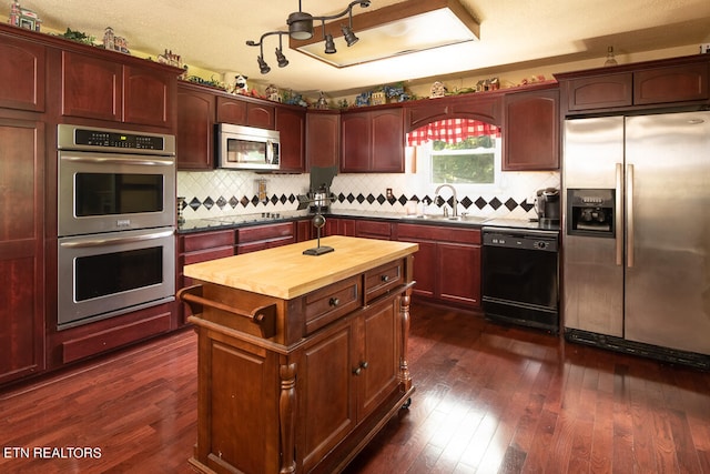 kitchen with a center island, tasteful backsplash, butcher block counters, black appliances, and dark hardwood / wood-style floors