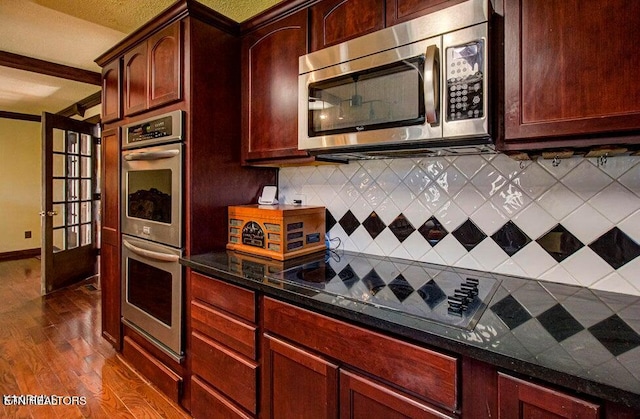 kitchen featuring backsplash, dark stone counters, stainless steel appliances, and dark hardwood / wood-style floors