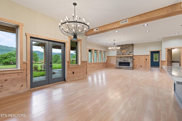 3119 Burns Rd, Sevierville, TN 37862 - unfurnished living room with a chandelier, french doors, a wainscoted wall, light wood-style flooring, and a fireplace