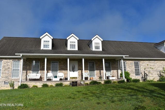 cape cod home featuring covered porch and a front yard