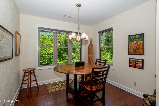 dining space with a healthy amount of sunlight, dark hardwood / wood-style floors, and an inviting chandelier