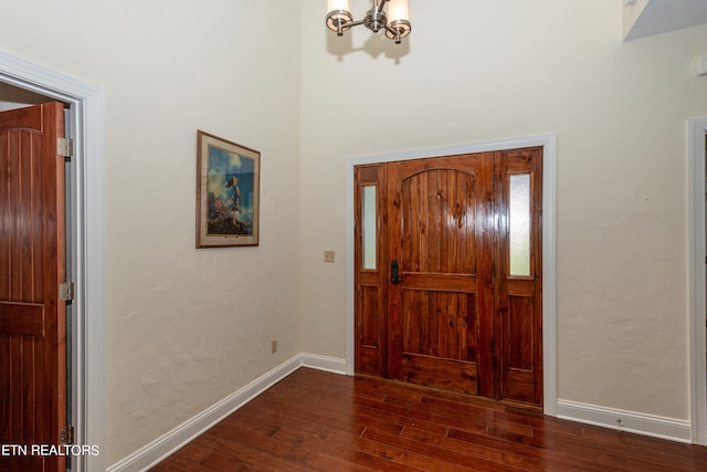 foyer entrance with dark wood-type flooring and an inviting chandelier