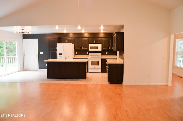 kitchen with lofted ceiling, white appliances, light hardwood / wood-style flooring, a kitchen island, and a chandelier