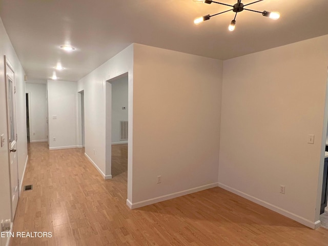 spare room featuring light hardwood / wood-style floors and a notable chandelier