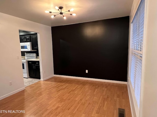 unfurnished room featuring a chandelier and light wood-type flooring