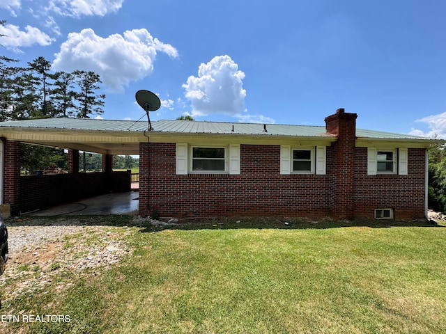 back of house featuring a carport and a lawn