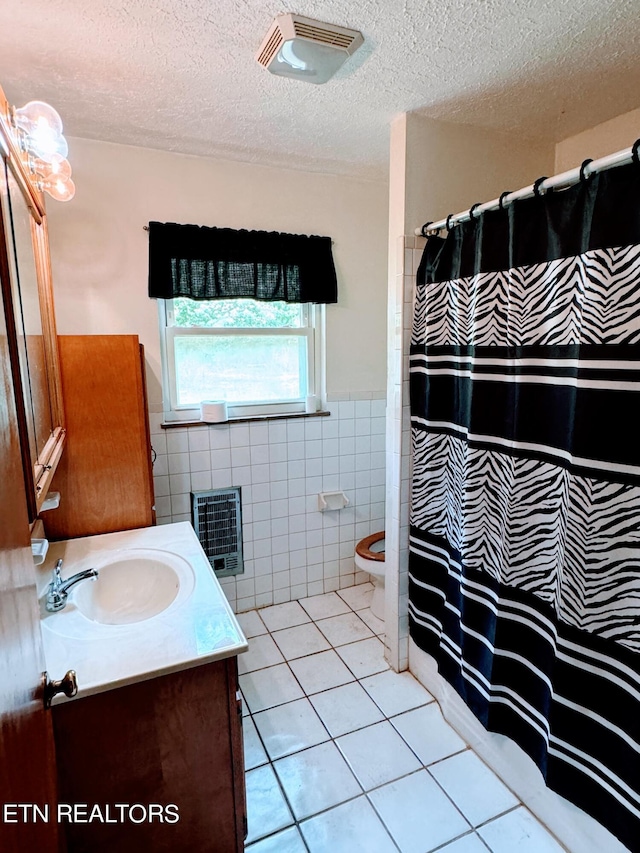 bathroom with tile patterned floors, vanity, tile walls, toilet, and heating unit