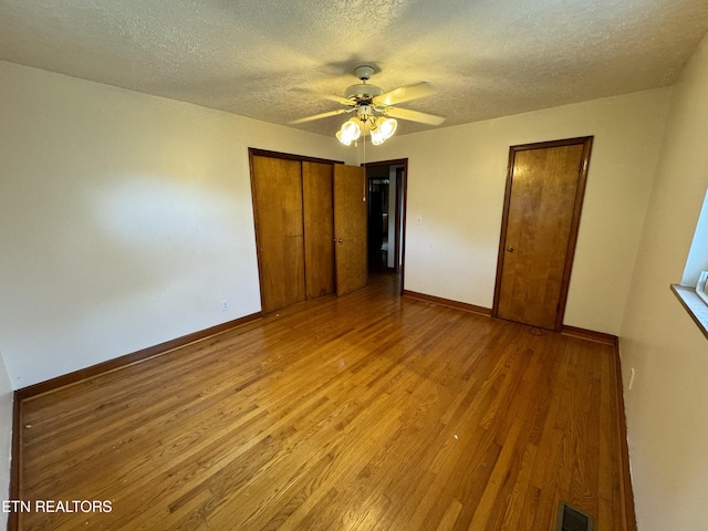 unfurnished bedroom with ceiling fan, a textured ceiling, light hardwood / wood-style flooring, and a closet