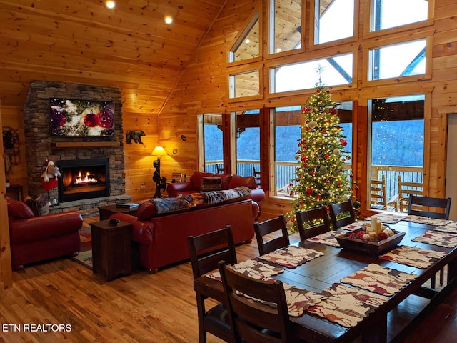 dining area with high vaulted ceiling, hardwood / wood-style flooring, and wooden walls