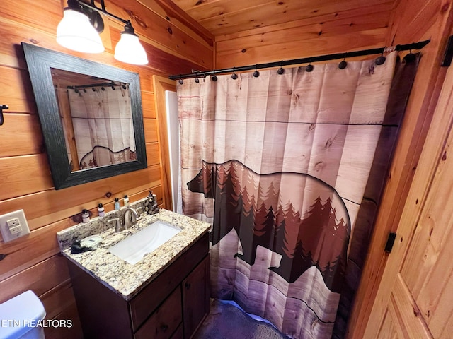 bathroom with wooden ceiling, wood walls, vanity, and toilet