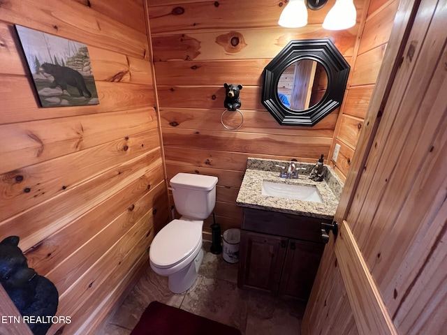 bathroom featuring large vanity, tile floors, toilet, and wooden walls