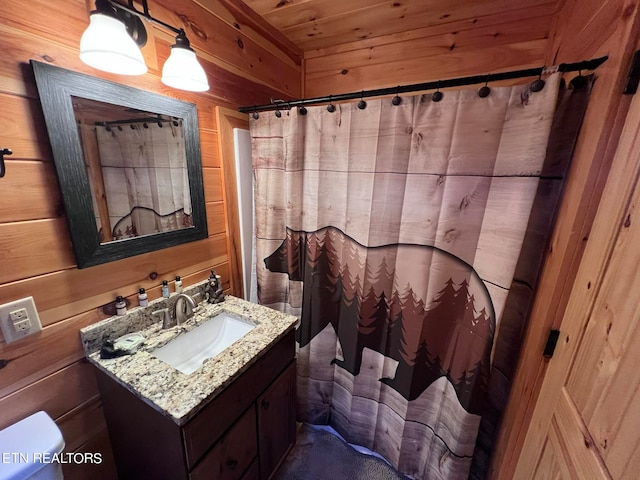 bathroom featuring wooden ceiling, vanity, toilet, and wooden walls