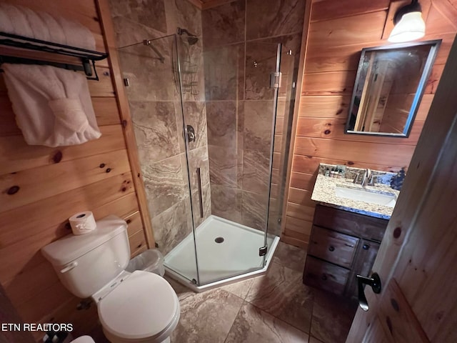 bathroom with tile floors, toilet, wood walls, vanity, and a shower with door