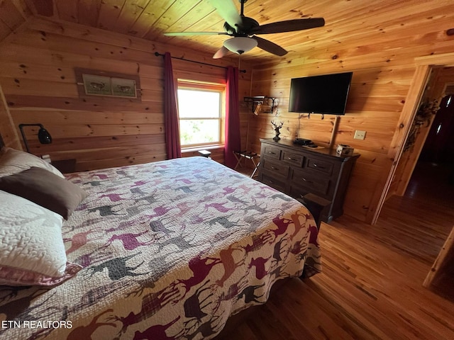 bedroom with wood-type flooring, wood ceiling, ceiling fan, and wooden walls