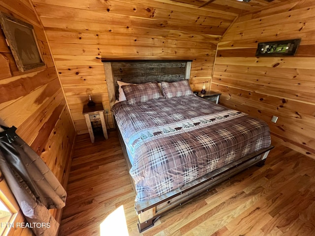 bedroom featuring wooden walls, vaulted ceiling, wooden ceiling, and hardwood / wood-style floors