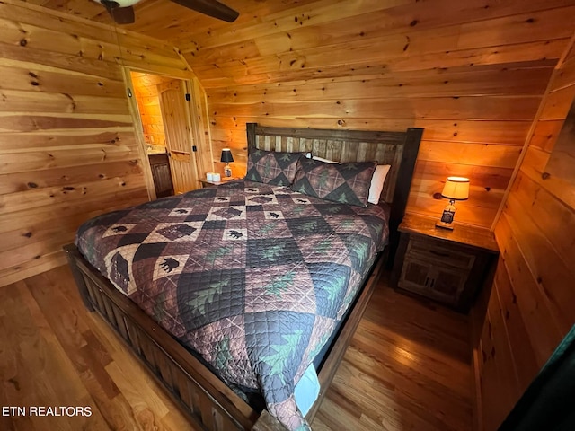 bedroom featuring wood-type flooring, wood walls, ceiling fan, and vaulted ceiling