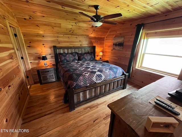 bedroom with wooden ceiling, wood walls, ceiling fan, and light wood-type flooring