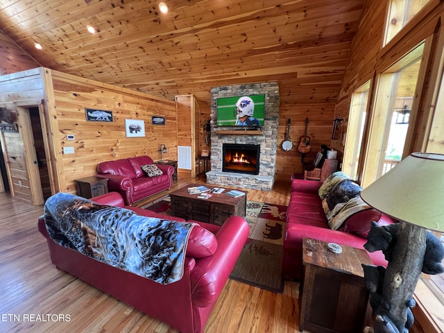 living room with a fireplace, hardwood / wood-style floors, vaulted ceiling, and wooden walls