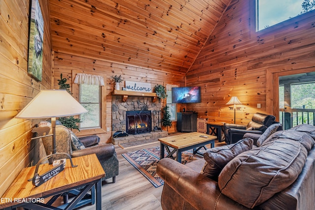 living room with a fireplace, hardwood / wood-style flooring, wooden walls, and a healthy amount of sunlight