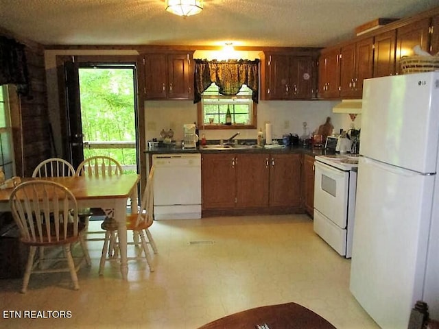 kitchen featuring plenty of natural light, white appliances, light tile floors, and exhaust hood