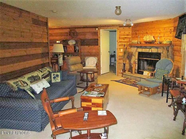 living room featuring carpet flooring, wooden walls, and a stone fireplace