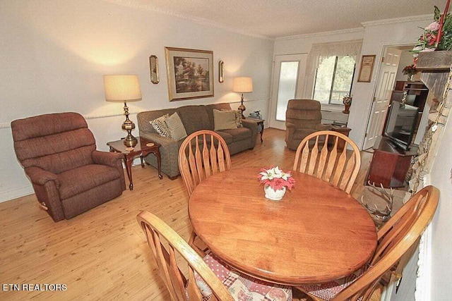 dining space featuring ornamental molding, light hardwood / wood-style floors, and a textured ceiling