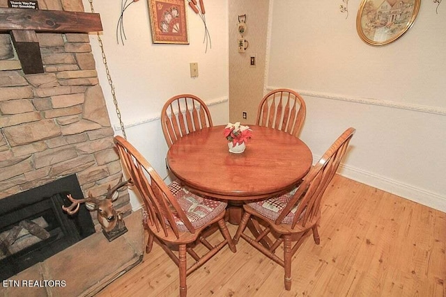 dining room with light hardwood / wood-style floors and a fireplace