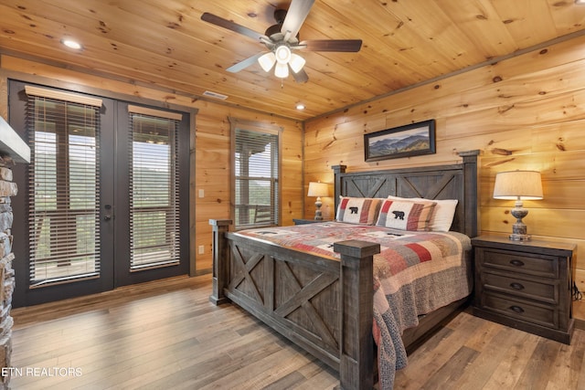 bedroom with access to outside, light hardwood / wood-style floors, wooden walls, and wood ceiling