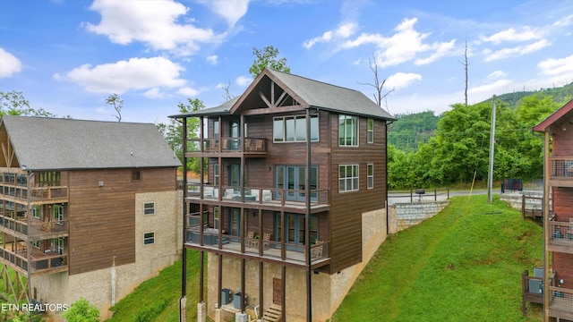 back of property featuring a balcony and a lawn