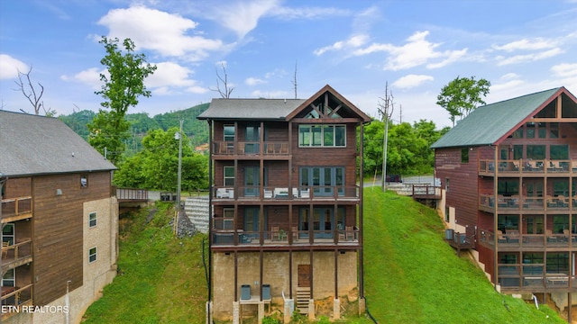 rear view of house featuring a balcony and a lawn