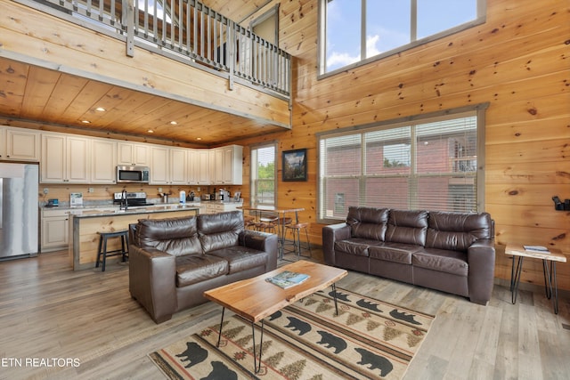 living room featuring light hardwood / wood-style floors, wooden walls, a high ceiling, and wooden ceiling