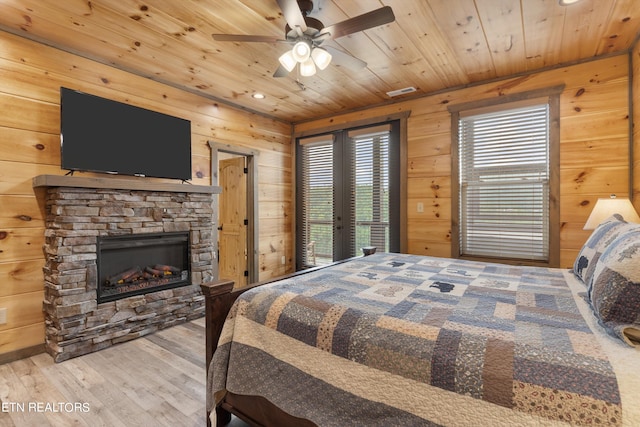 bedroom with light hardwood / wood-style flooring, a fireplace, ceiling fan, wooden ceiling, and french doors