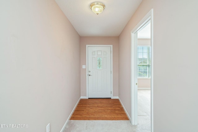 entryway with baseboards and light carpet