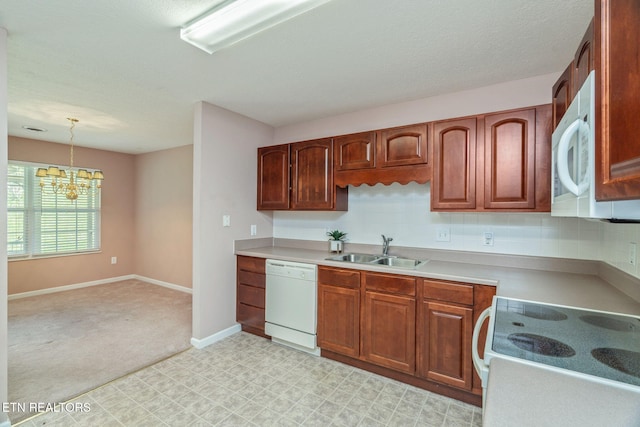 kitchen with a sink, an inviting chandelier, white appliances, pendant lighting, and light countertops