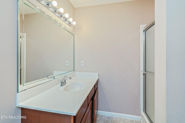 full bath with baseboards, vanity, and a shower with shower door