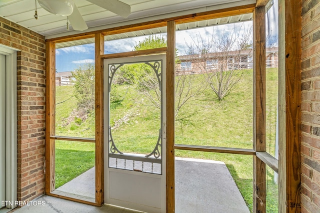 doorway to outside with brick wall and a ceiling fan